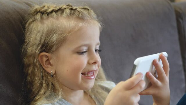 Cute baby having fun with a mobile phone. A little girl in her free time plays a mobile game. Concept: Happy childhood, Games for children
