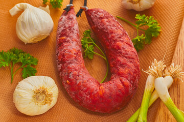 Flat lay of some chorizo sausage,with some garlic and onions resting on some baking paper.