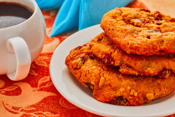 Cup of coffee and cookies, the cookies are stacked on a white plate,there is also a blue napkin in the background.