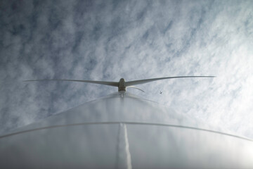 Aerogenerador y avión volando encima de la turbina