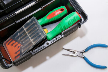 Screwdrivers are in a gray open tool box, pliers are nearby