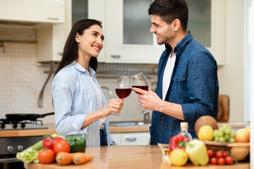 Lovely couple drinking wine together in kitchen at home