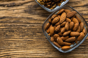 Almond and walnut in a small plates which standing on a wooden vintage table. Nuts is a healthy vegetarian protein and nutritious food. Nuts on rustic old wood.
