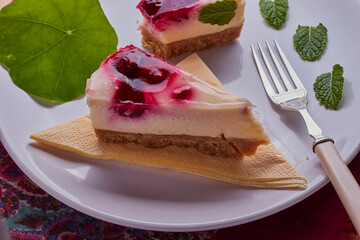 Pieces of raspberry cheese cake, on a white plate with some mint leaves.