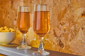 Couple of flute glasses full of wine, next to a marble background.