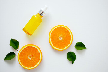 Vitamin C serum in cosmetic bottle with dropper and slices of orange on white background. Organic bio cosmetics with vitamin C. Homeopathic essential oil, nutritional supplements. Flat lay minimalism.