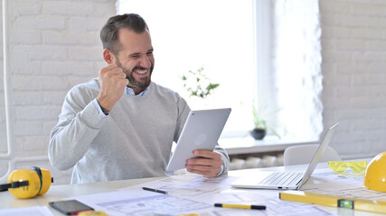 Young Architect Celebrating Success on Tablet in Office