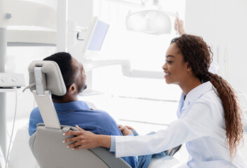 Obraz premium Black lady stomatologist greeting man at clinic