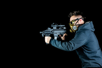 Man in gas steampunk mask with goggles and submachine gun. Steampunk theme photo with black background. Man targets a submachine gun.