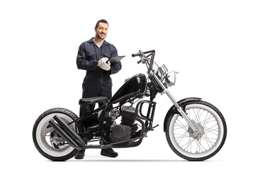 Obraz na płótnie Canvas Motorbike mechanic standing behind a chopper and holding a clipboard