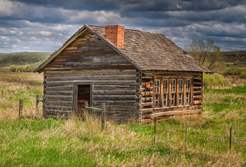 An abandoned  log house  along the highway .
