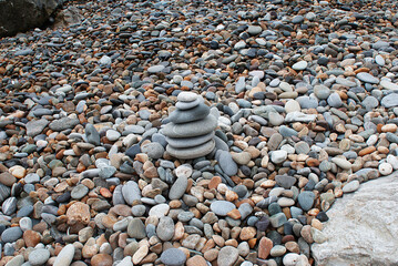 Fototapeta na wymiar Pyramid of round stones on the seashore, the concept of harmony, balance and meditation.