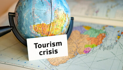 Tourism crisis text on a white sheet on globe on the blue background of the atlas map