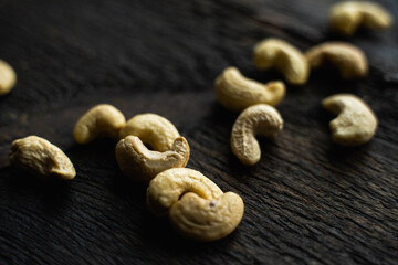 Cashew nuts scattered on the wooden vintage table. Cashew nut is a healthy vegetarian protein nutritious food.