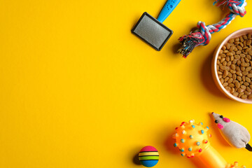 Pet care and training concept. Flat lay composition with toys for cat and dog and bowl with dry food on yellow background.