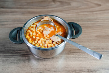 Traditional Turkish food chickpea in  saucepan with ladle on brown table. Chickpea soup.