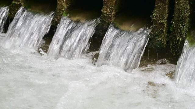 Water flows through pipes inder an old bridge