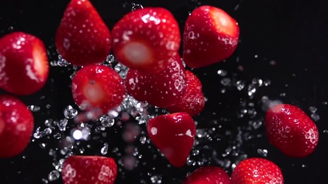 Strawberry explosion with water on a black background. Slow motion 500 fps
