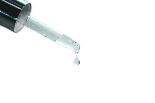 A pipette from cosmetic glass dropper with a little drop on its end.