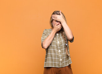 young pretty latin woman covering face with both hands saying no to the camera! refusing pictures...