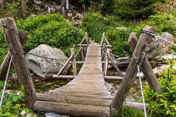 Old wooden bridge crossing over mountain stream in Romanian mountains