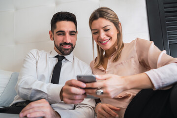 Business people lying on bed and using mobile phone.