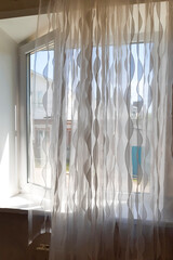 An open window into summer with a long tulle and curtains.