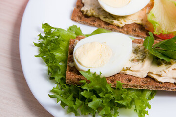 raunchy crisps bread with hummus egg and greens on a plate, proper and healthy nutrition concept, dietetic breakfast foods, crisps sandwich, close-up