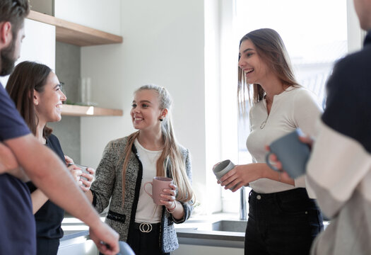 Smiling friends meeting with mugs of tea