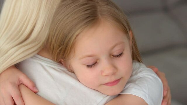 Happy cute affectionate adopted little kid girl hugging foster care parent mother with eyes closed, adorable small child daughter embrace mum cuddling enjoy tender sweet moment concept, close up view