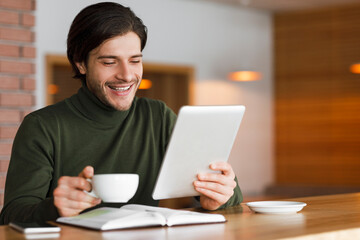 Freelancer having morning coffee at cafe, checking news on tablet