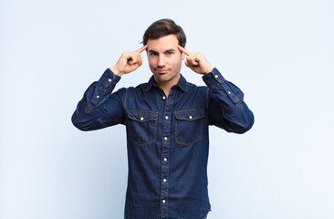 young handsome man looking concentrated and thinking hard on an idea, imagining a solution to a...