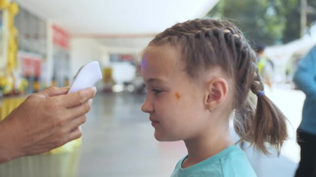 Temperature check at a supermarket of little girl, grocery store with thermal imaging camera installed. Image monitoring scanner to monitor the body temp of visitor child baby. Coronavirus Covid-19.