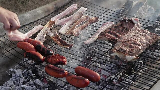 Parrilla con panceta, costillas y chorizo sobre el fuego.