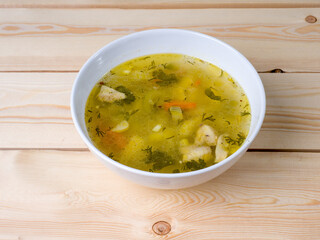 Chicken soup in a bowl on a wooden surface. Hot dish