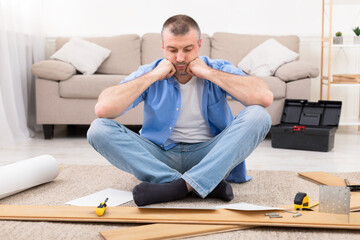 Man Sitting Near Disassembled Shelf Having Problems Installing Furniture Indoor