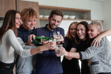 Cheerful young friends opening bottle of champagne