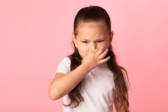 Shocked girl smelling something stinky at studio