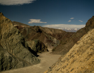 Andes mountains landscape. Transport. Dirt road in the arid desert mountains in Barreal, San Juan, Argentina. Geology. Rocky hills made of different minerals, with different colors and textures