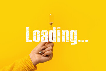 hourglass in hand over yellow background, loading concept