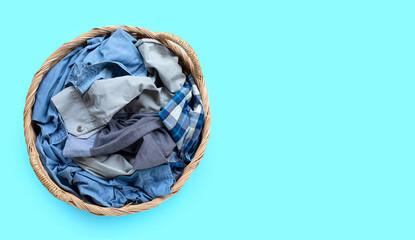 Clothes in laundry basket on blue background.