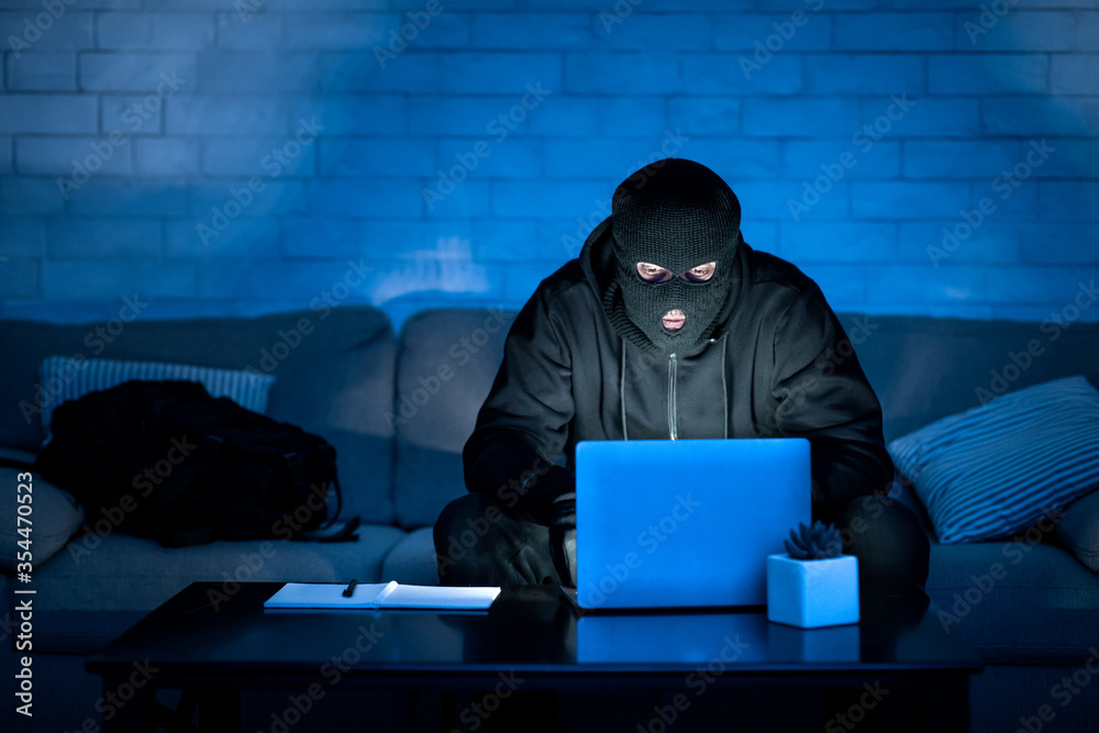 Poster Masked hacker downloading private information off a computer