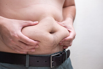 Unhealthy, Metabolism concept, Man gripping big belly with visceral or subcutaneous fats. Pose...