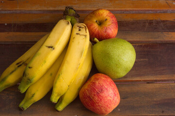 Colorful fresh summer fruits on brown wooden background, healthy organic food on table, detox vitamin nutrition for health care, top close up view, copy space