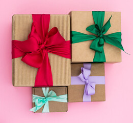 Gifts in craft paper with colorful ribbons on a pink background. Top view.