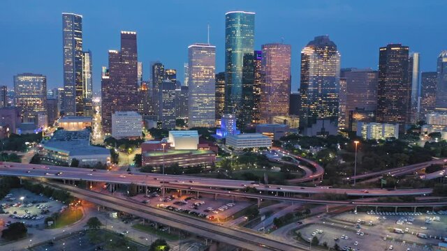 Aerial: Downtown Houston skyscrapers & freeway interchange at night. Texas, USA