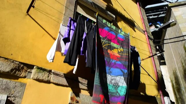 Low angle panning shot of clothes hanging outside window in city on sunny day - Porto, Portugal