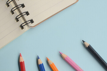 top view empty space with colored pencils and notebooks on a blue background
