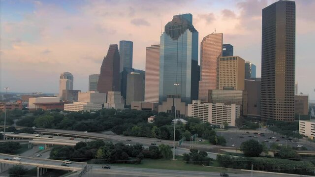 Aerial: Downtown Houston skyscrapers & freeway traffic at sunset. Texas, USA