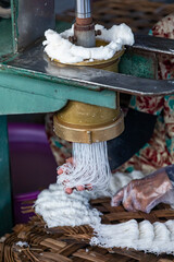 A woman making rice noodles with machine in traditional Vietnamese style in closeup.